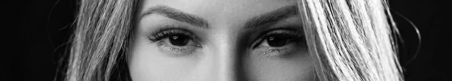 Faixa estreita do retrato em preto e branco: só os olhos da Dra. Marina Raposo, olhando para a câmera