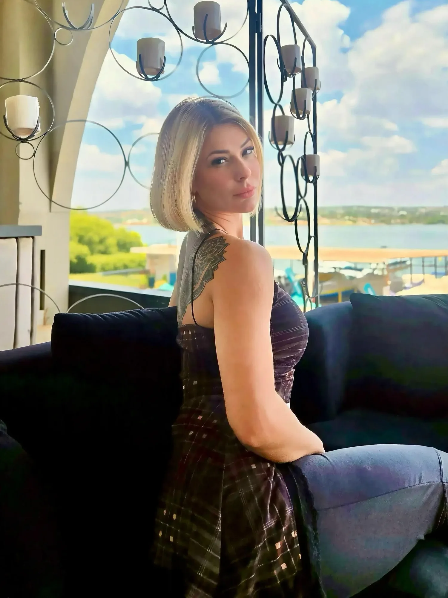 Dra. Marina Raposo sentada, de costas para a câmera, olhando para trás por cima do ombro; ao fundo, uma janela com vista para o lago